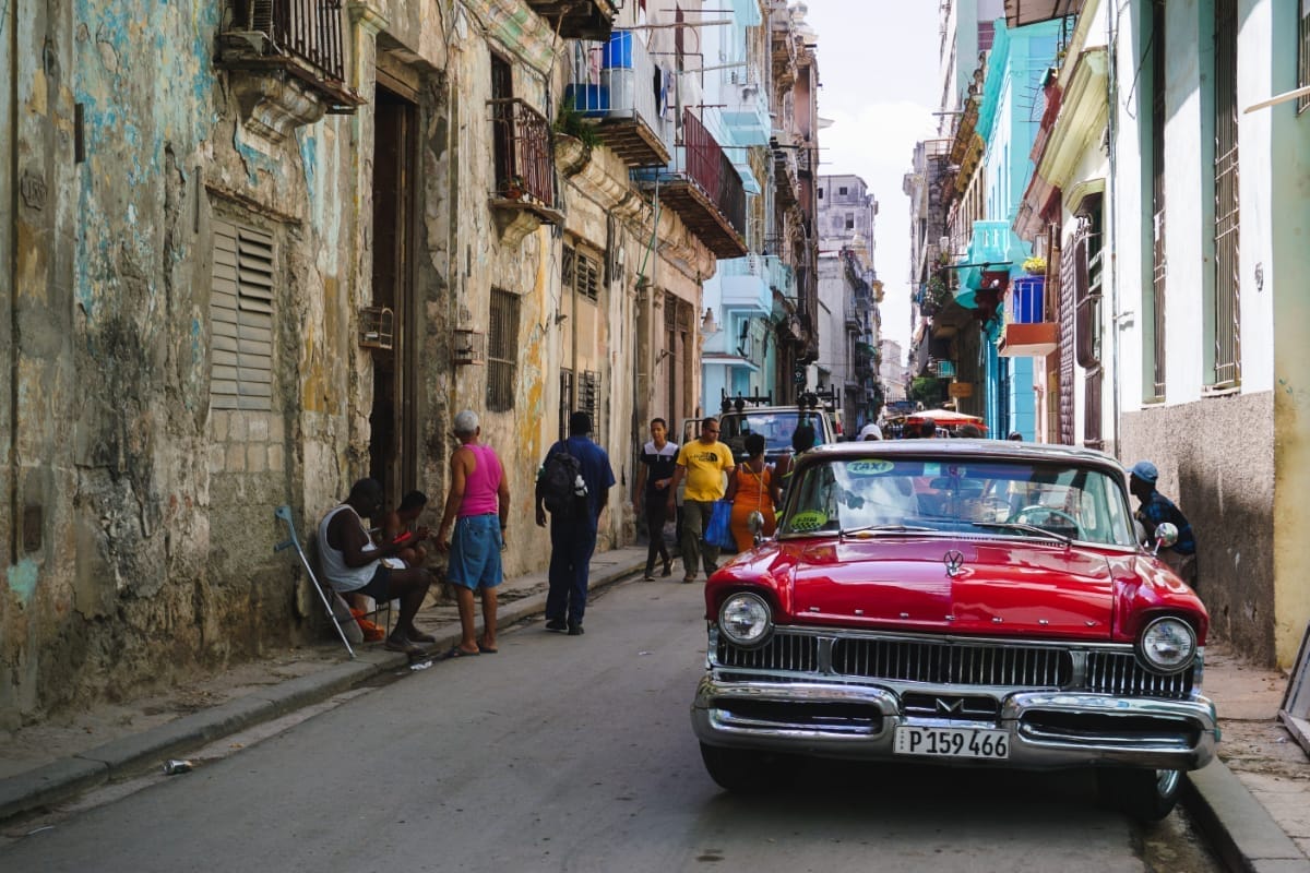 Straßenscene in Santiago de Cuba, roter Oldtimer